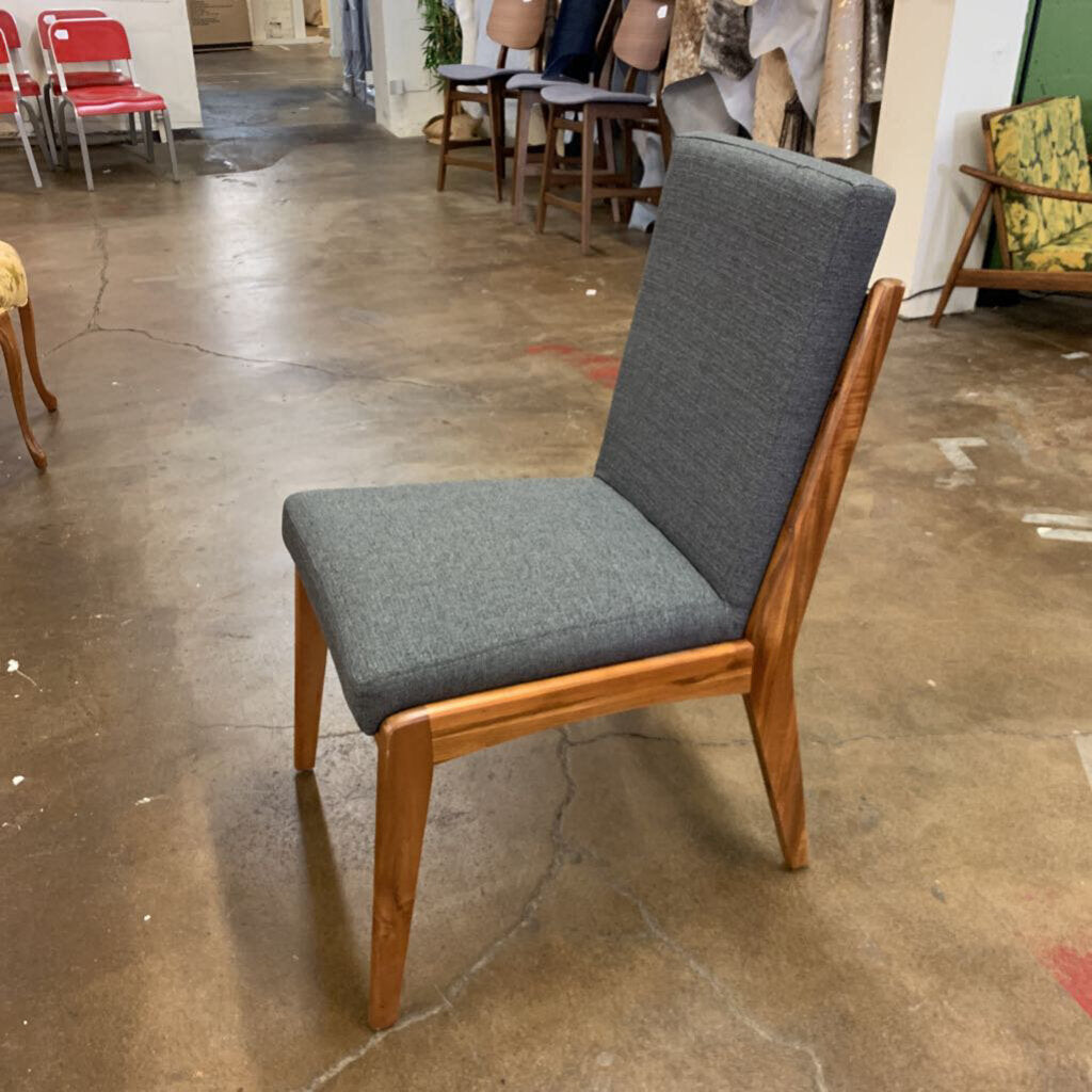 Chair with gray cushioned seat and backrest on a concrete floor in an indoor setting.
