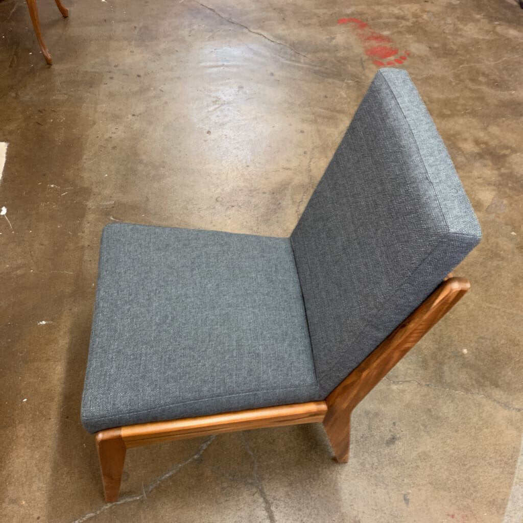 Gray upholstered chair with wooden frame on a concrete floor