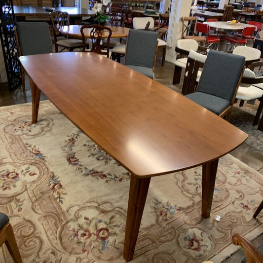 Wooden dining table with chairs in a room with patterned rug and furniture.