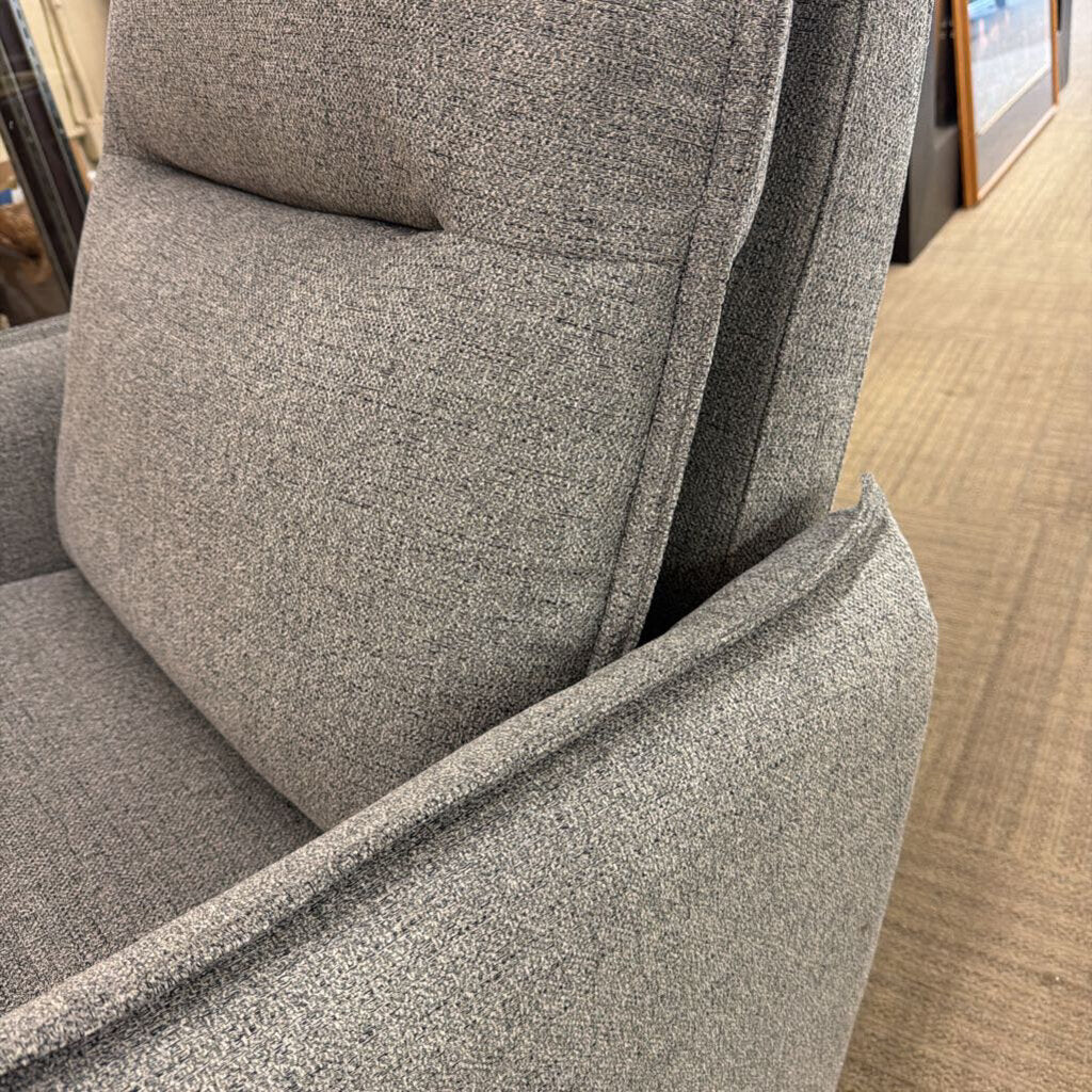 Gray upholstered chair with a textured fabric finish on a wooden floor.