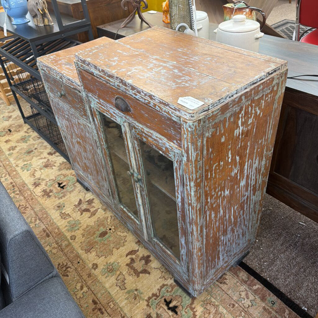 Vintage wooden cabinet with peeling paint on a patterned rug