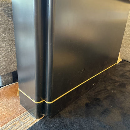 Black book with gold spine on a textured surface