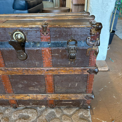 Vintage wooden trunk with metal hardware on a carpeted floor.