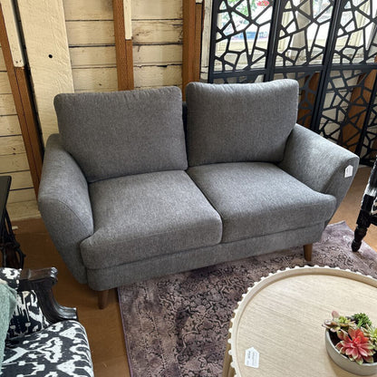Gray sofa in a showroom with other furniture and decor items.