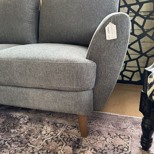 Gray sofa with a price tag on a patterned rug