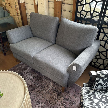 Gray sofa in a room with wooden walls and a patterned rug.