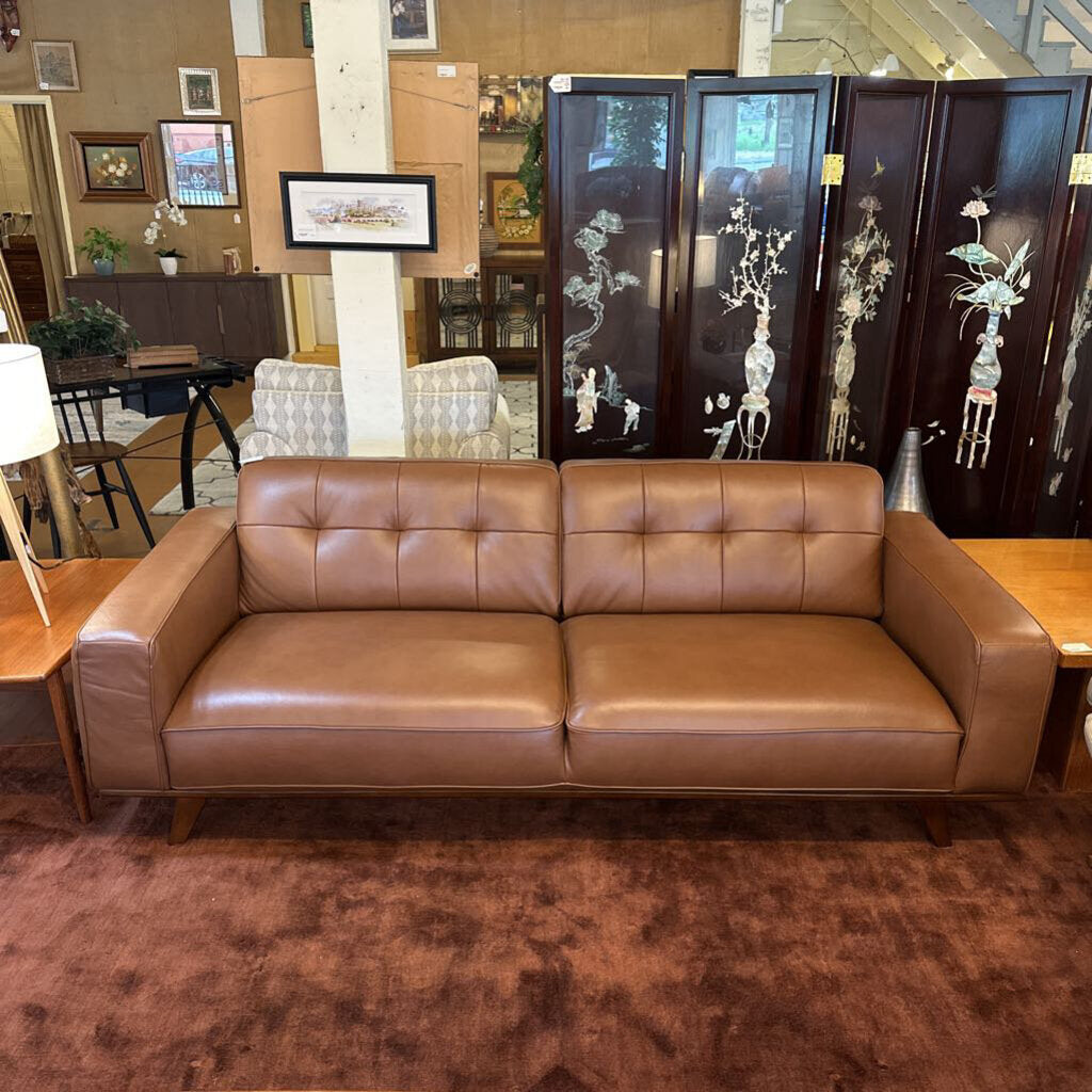 Brown leather sofa in a room with decorative screens and furniture.