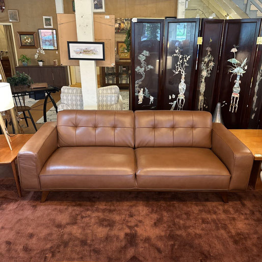 Brown leather sofa in a room with decorative screens and furniture.