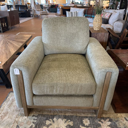 Beige armchair in a furniture store setting with wooden legs