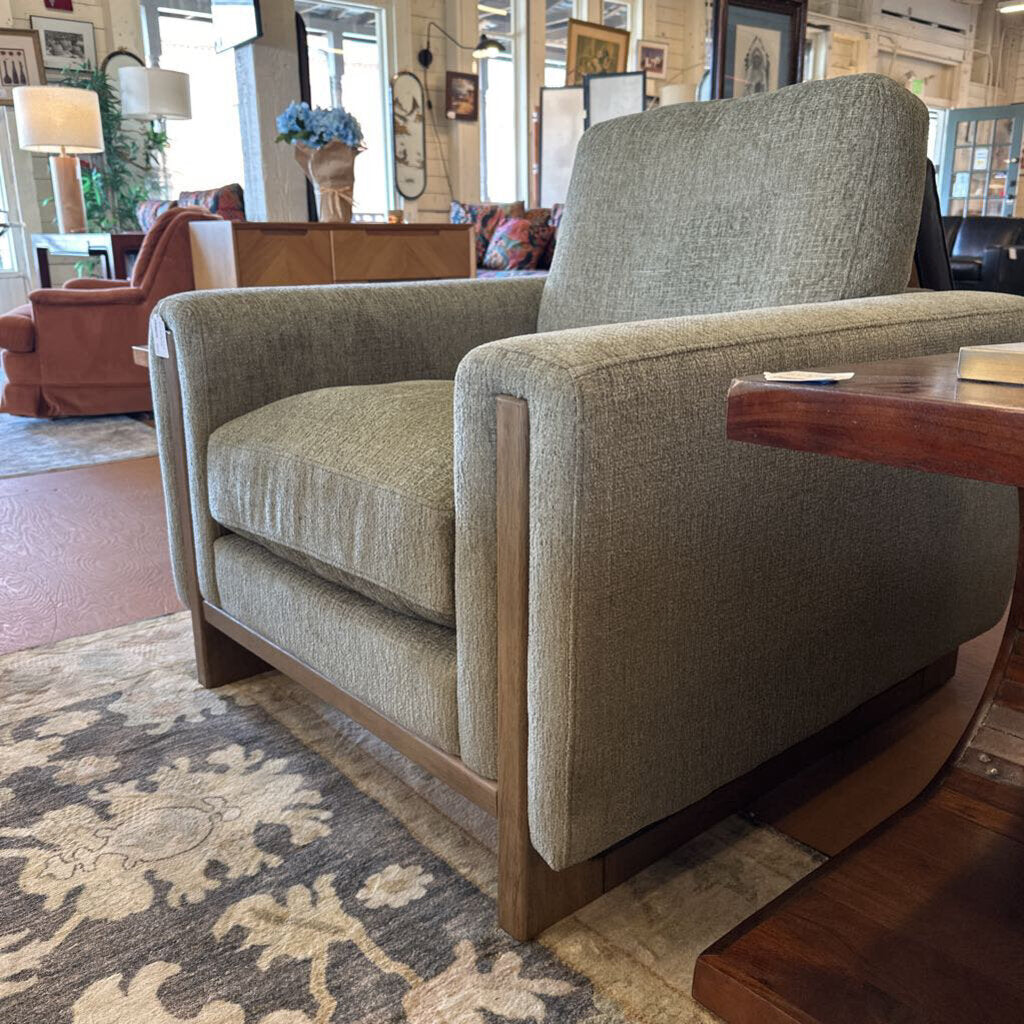 Gray armchair in a room with a patterned rug and wooden floor.