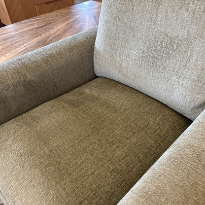 Close-up of a textured beige sofa with wooden floor in the background