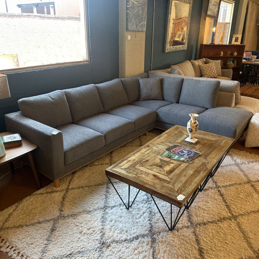 Gray sectional sofa in a living room with a wooden coffee table and decorative items.