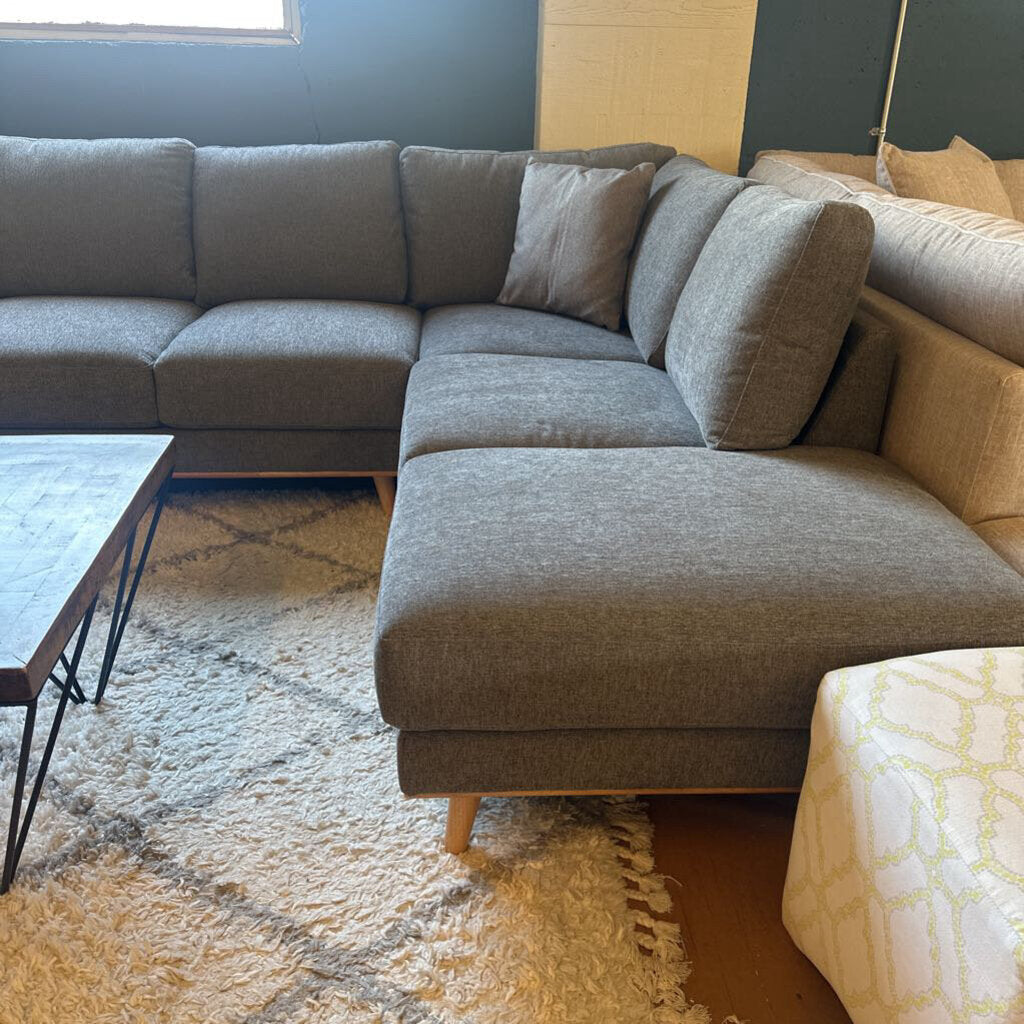 Gray sectional sofa in a living room setting with a rug and coffee table.
