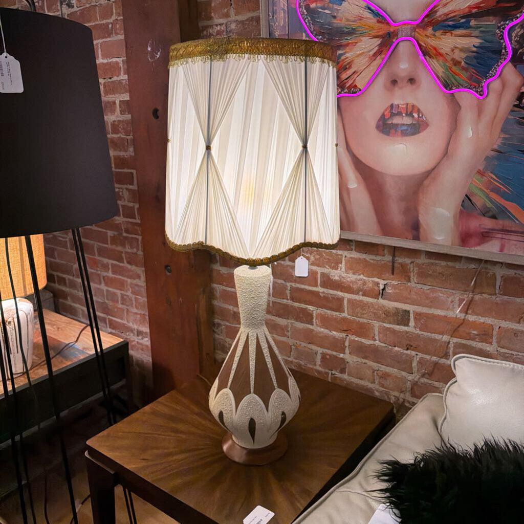 Decorative lamp with a unique shade on a table against a brick wall.