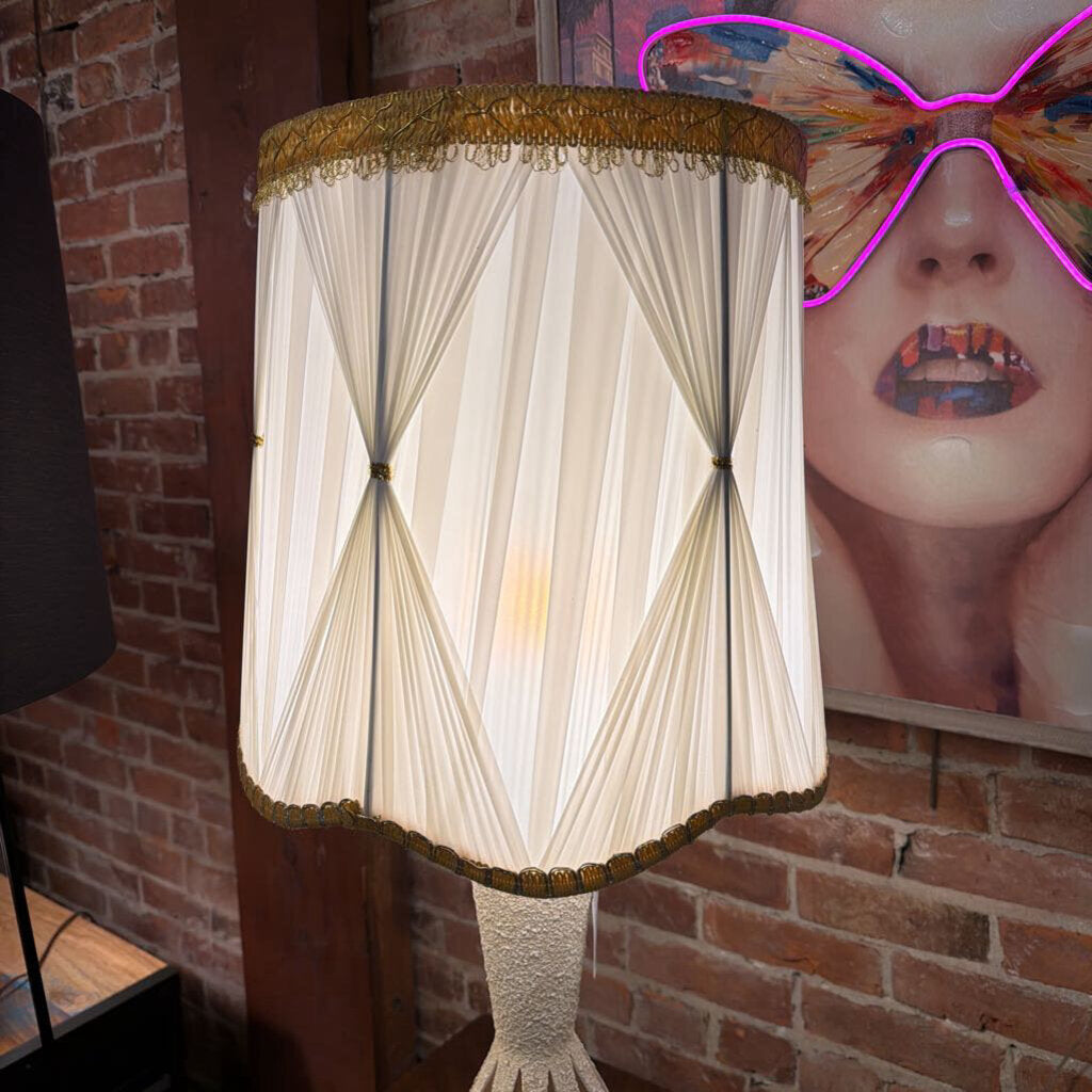Decorative lamp with pleated shade against a brick wall