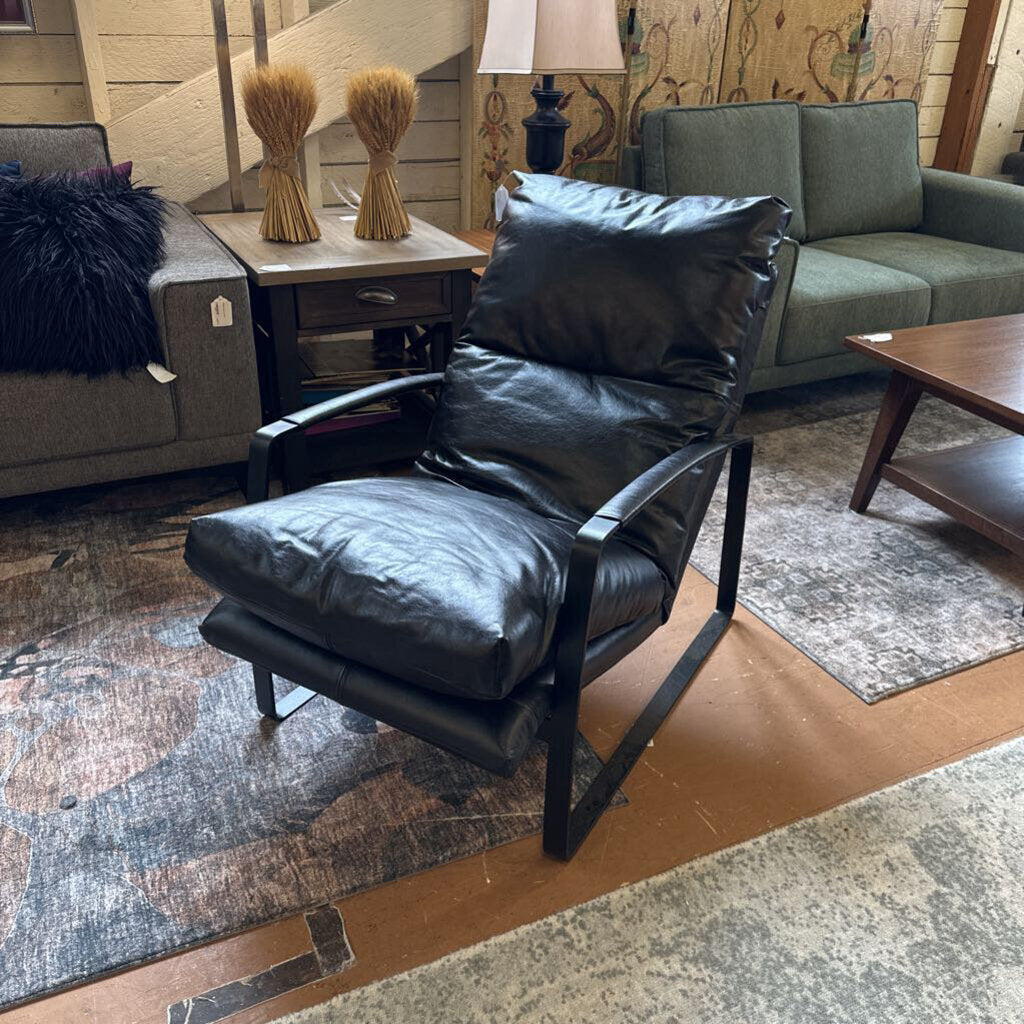 Black leather chair in a living room setting with furniture and decor.