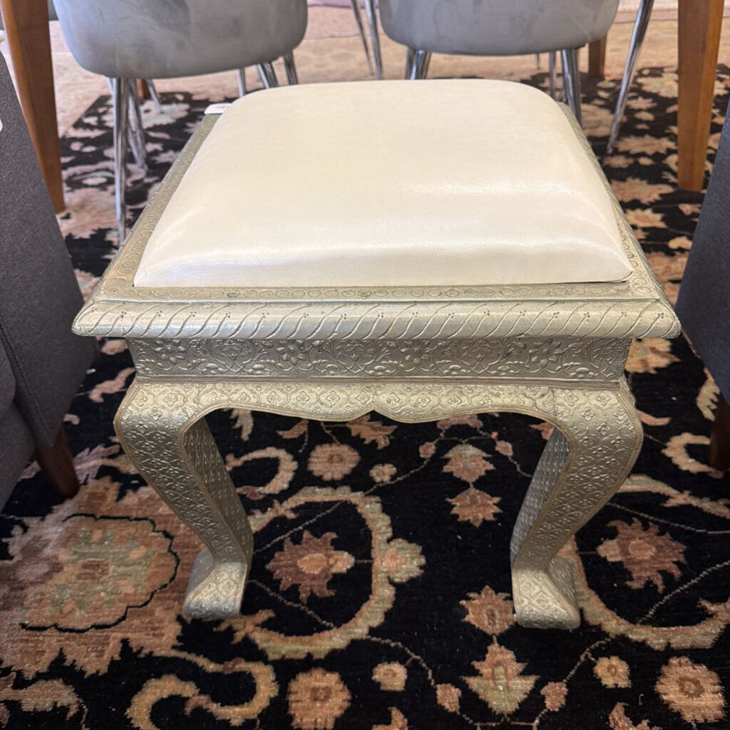 Decorative stool with a white cushion on a patterned rug