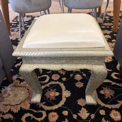 Decorative stool with a white cushion on a patterned rug