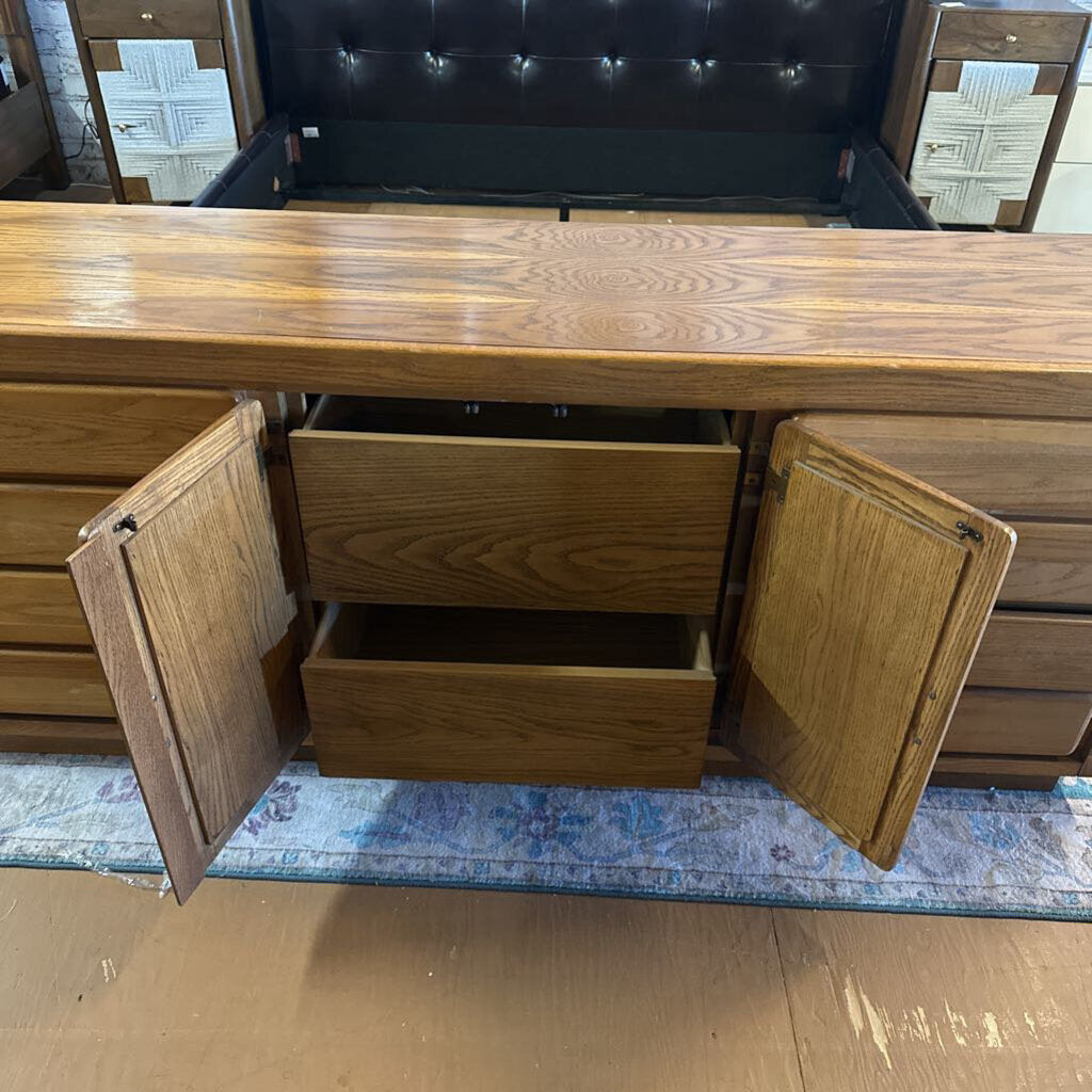 Wooden dresser with open doors and drawers on a wooden floor.