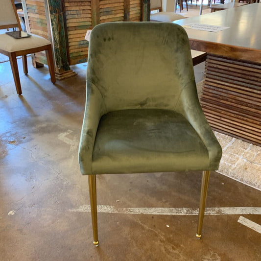 Green velvet chair with gold legs on a stone floor