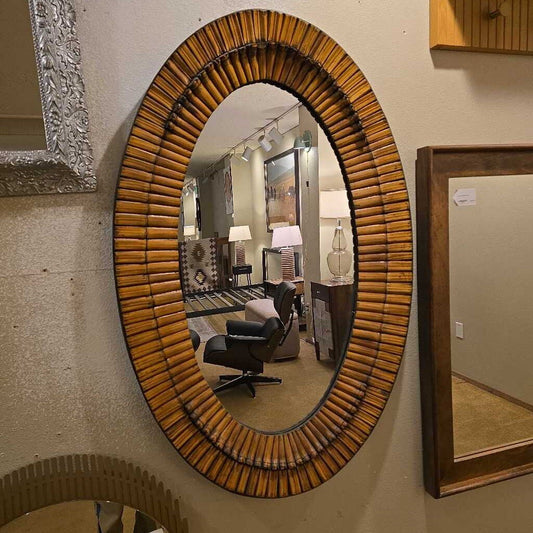 Round mirror with wicker-like frame on a wall