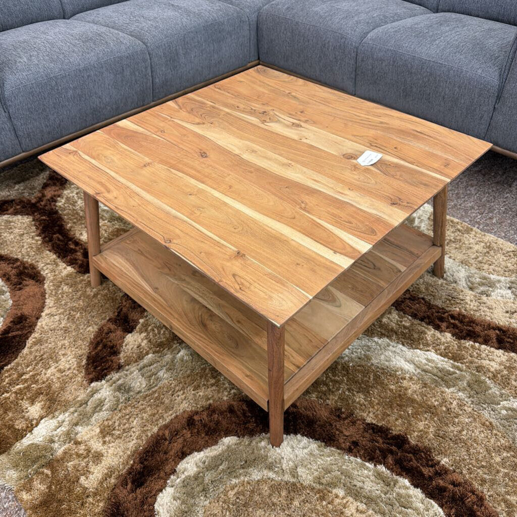 Wooden coffee table in front of a gray sectional sofa on a patterned rug