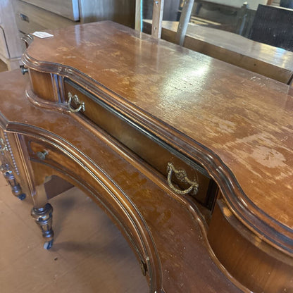 Vintage wooden desk with curved design and ornate details.