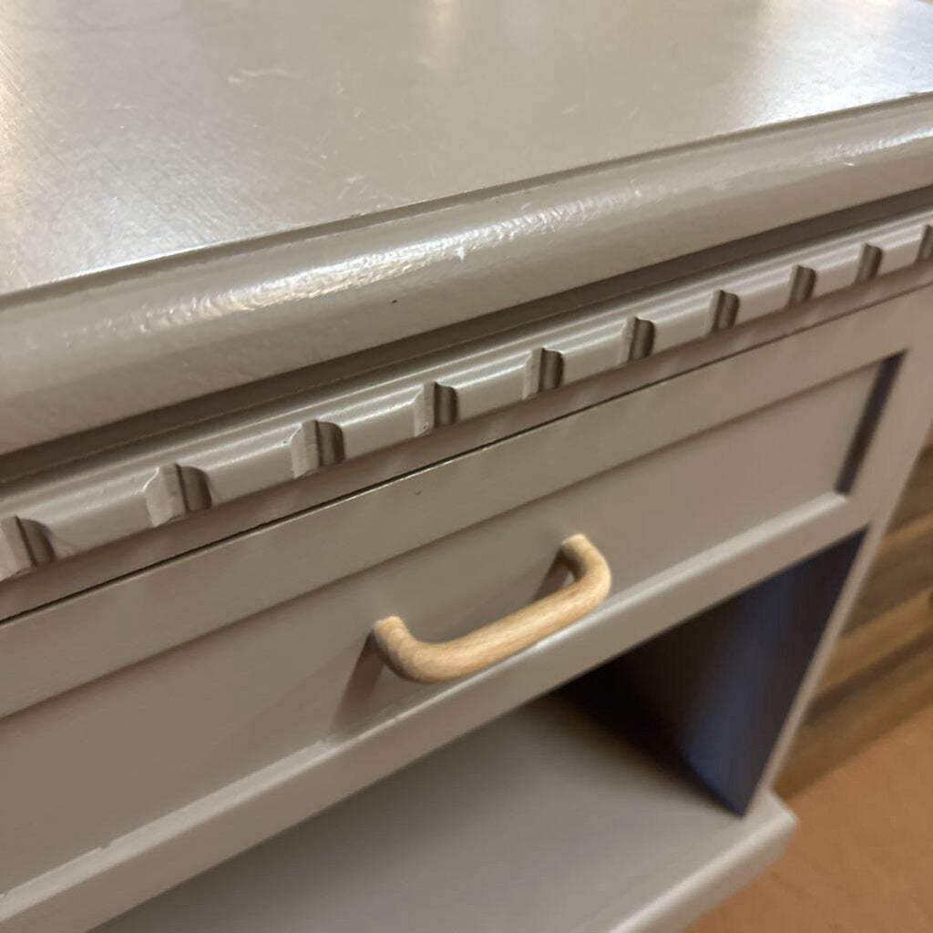 Close-up of a beige drawer with a handle on a wooden surface