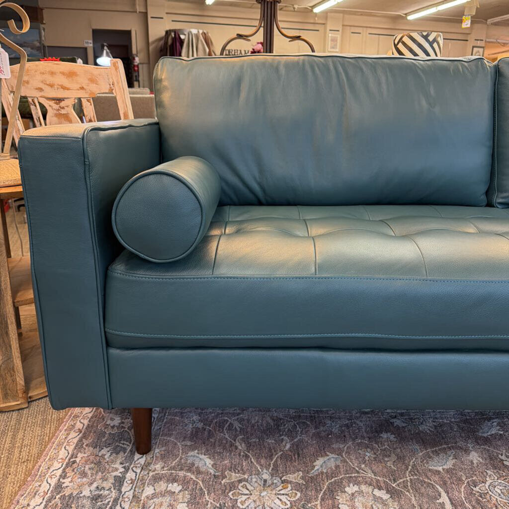 Blue leather sofa in a room with furniture and decor.