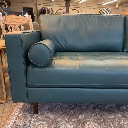 Blue leather sofa in a room with furniture and decor.