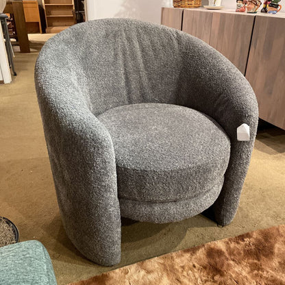 Gray textured armchair in a room with wooden furniture.
