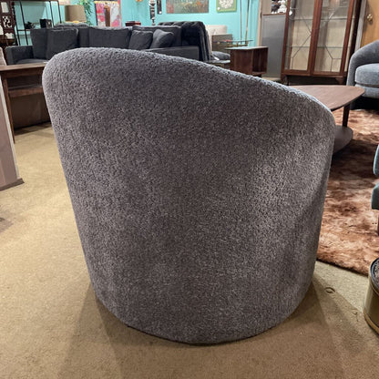 Gray textured chair in a room with a couch and tables.