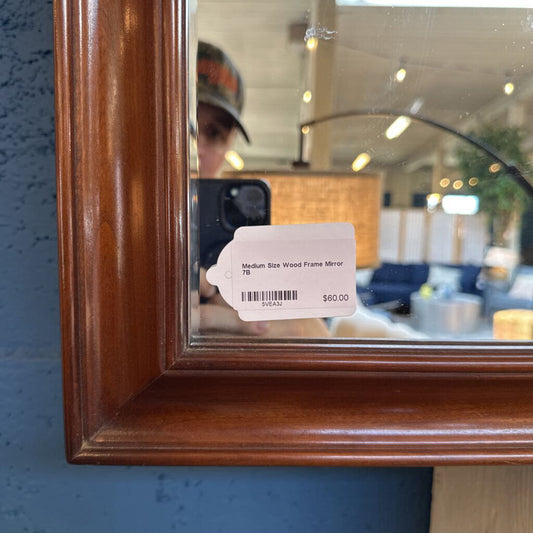 Wooden framed mirror with a price tag on a blue wall