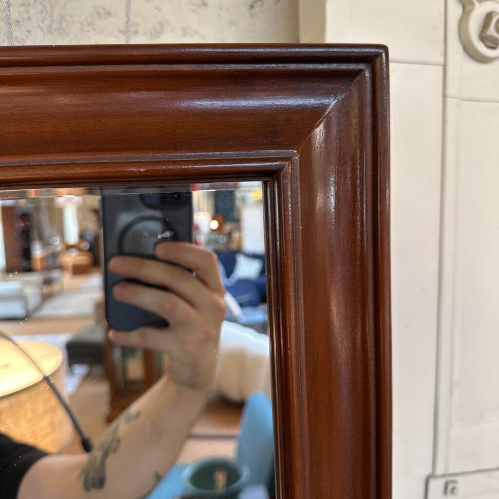 Person taking a mirror selfie with a wooden frame