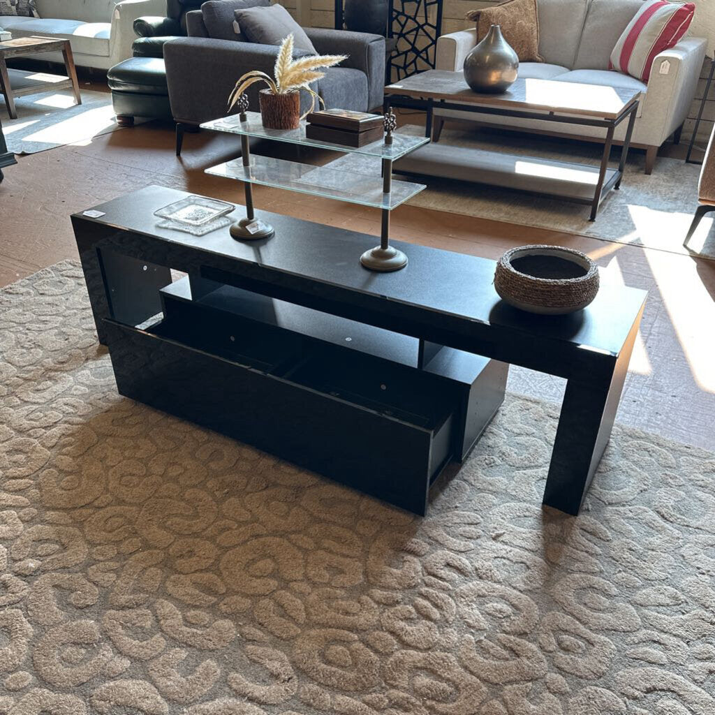 Black coffee table in a living room setting with decorative items.