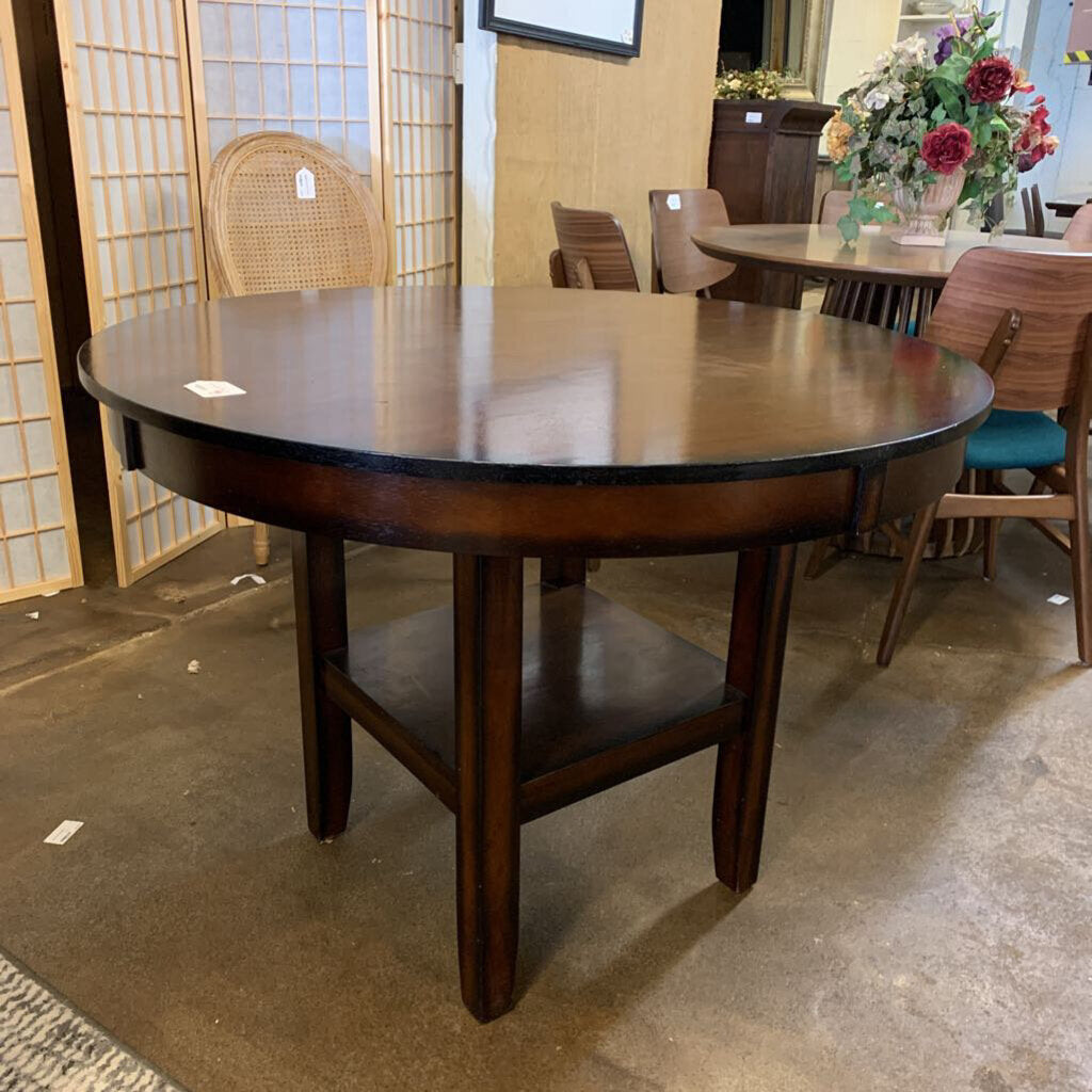 Wooden dining table in a showroom setting with chairs and decor.