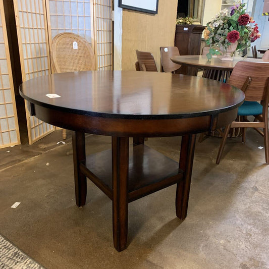 Wooden dining table in a showroom setting with chairs and decor.