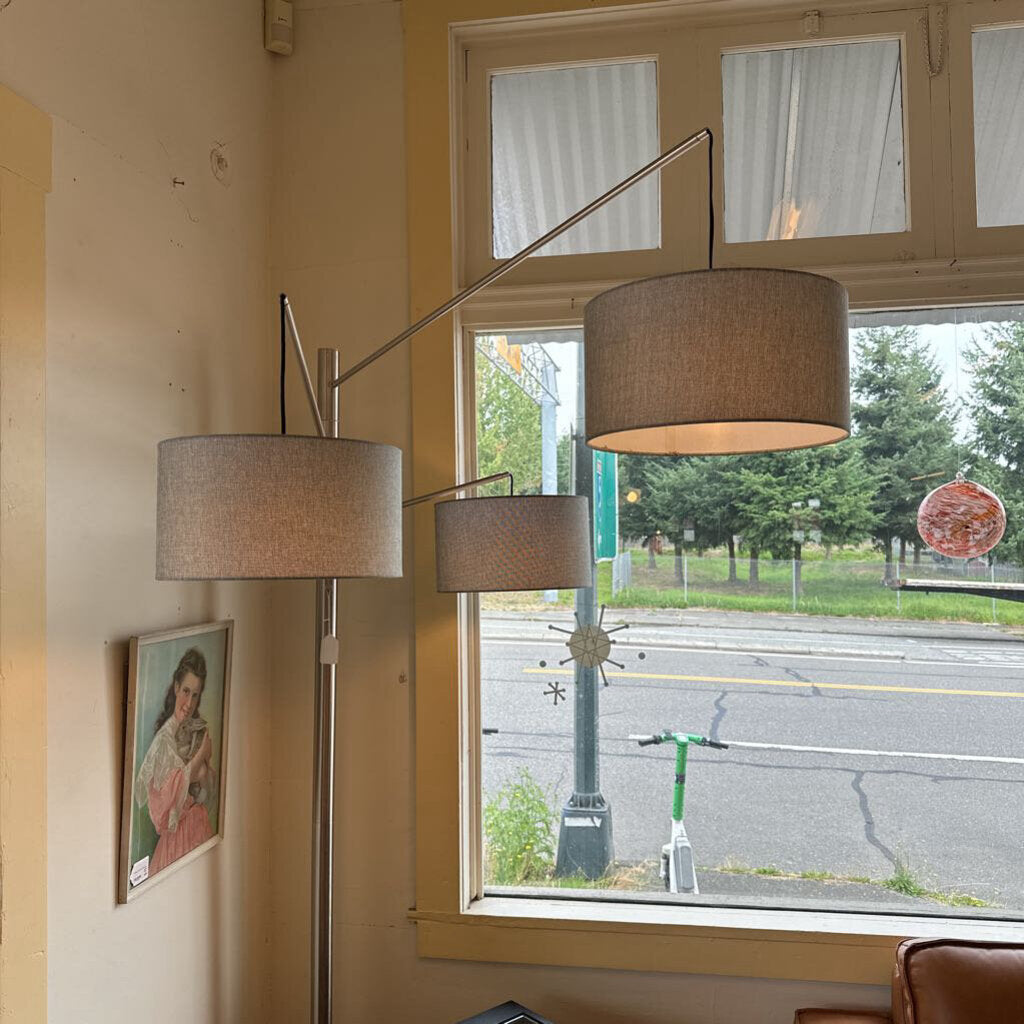 Floor lamp with two lampshades in a room with a window view of a street.