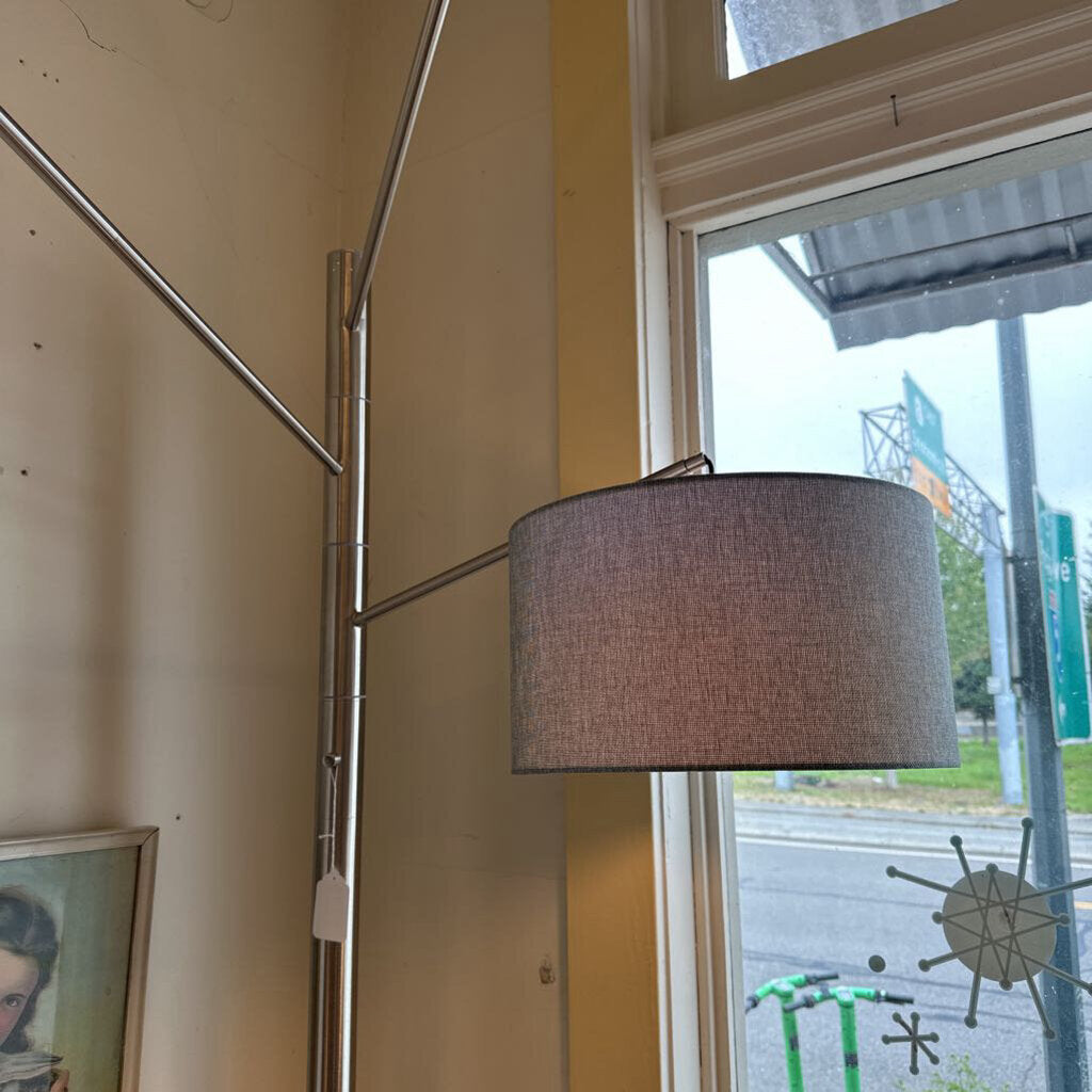 Floor lamp with a gray shade in a room with a window showing an outdoor view.
