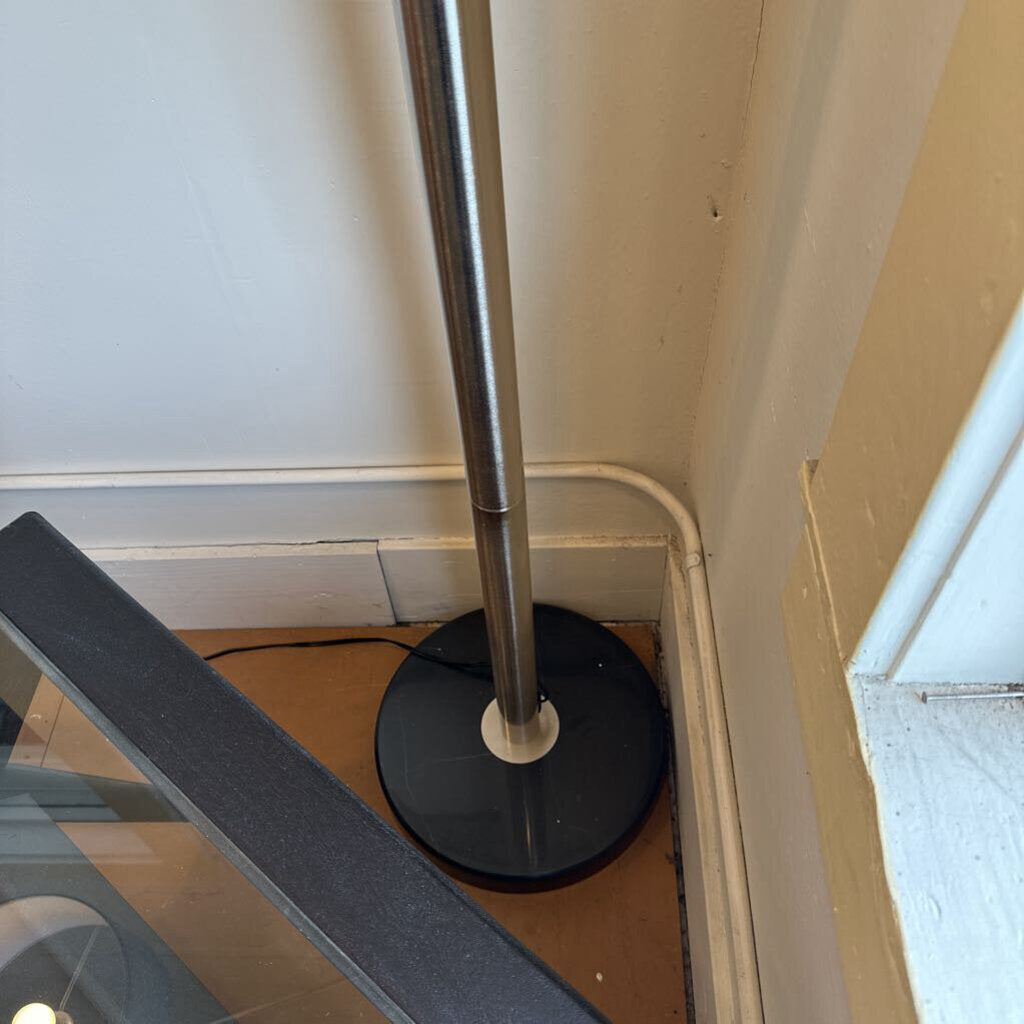 Metal stand with black base against a wall