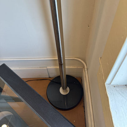 Metal stand with black base against a wall