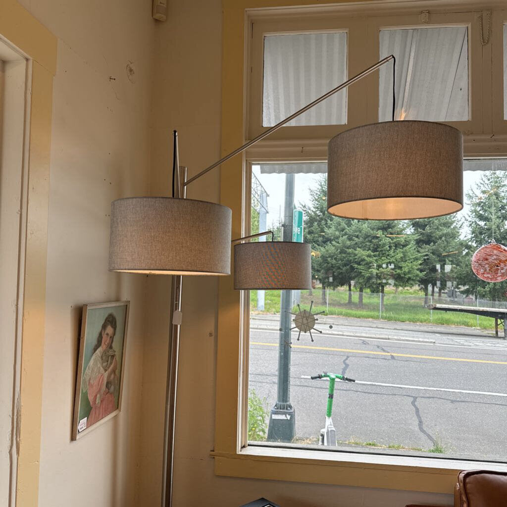 Floor lamp with brown lampshades in a room with a window showing an outdoor view.