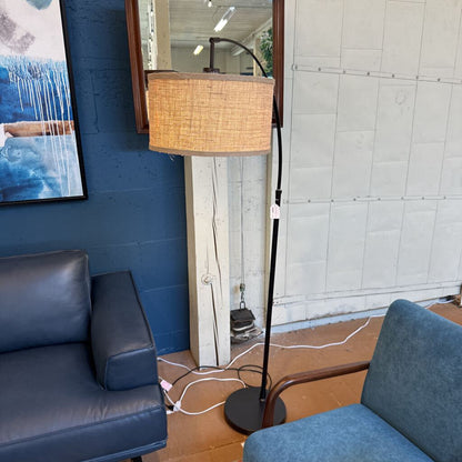 Futuristic lamp with wicker shade in a room with blue walls and a gray sofa.