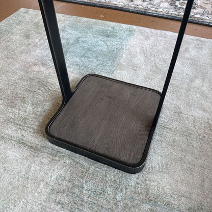Black metal stand with wooden base on a textured surface