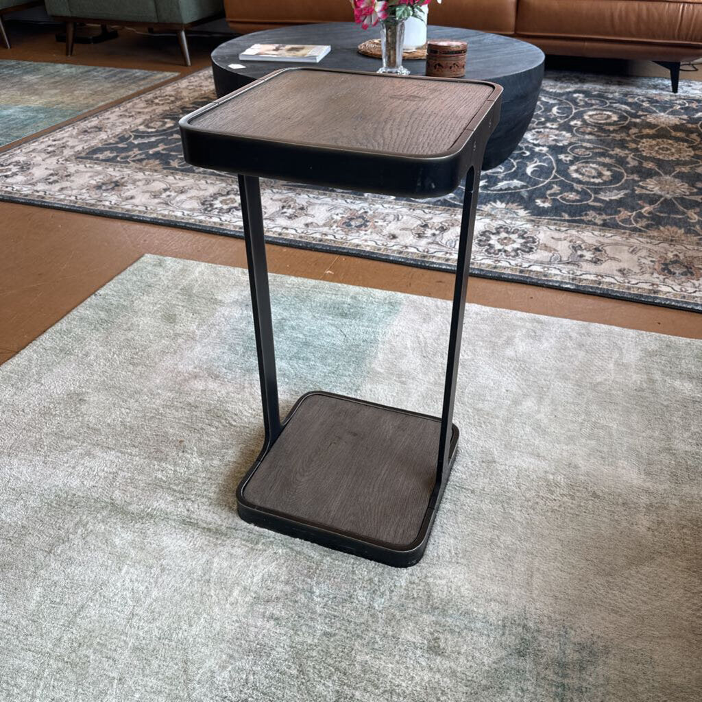 Small dark brown side table with black metal legs in a living room setting.