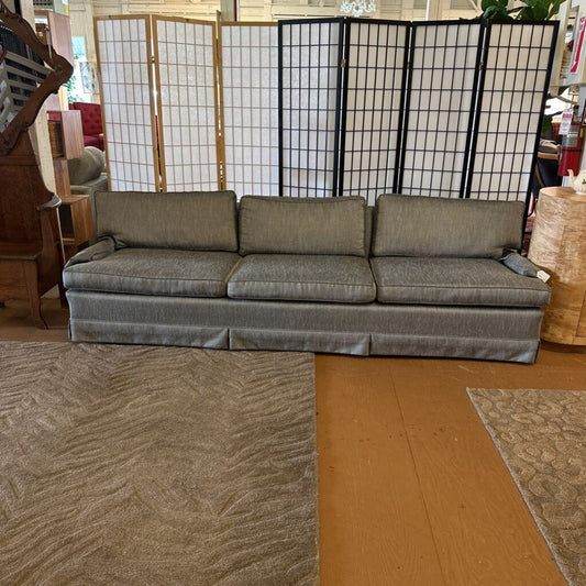 Gray sofa in a room with a wooden floor and a screen in the background