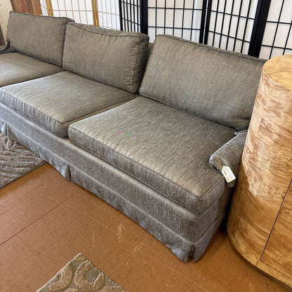 Gray sectional sofa in a room with wooden flooring and a decorative rug.