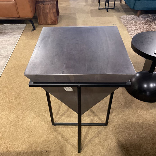 Square metal table with black legs on a carpeted floor