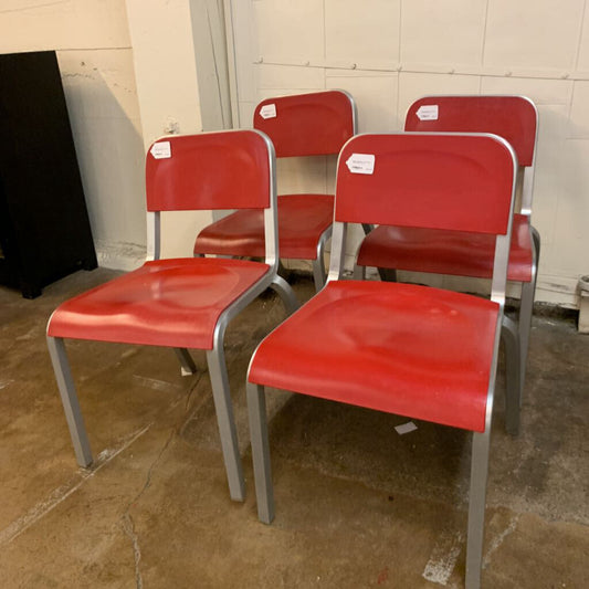 Four red chairs with metal legs in a storage area.