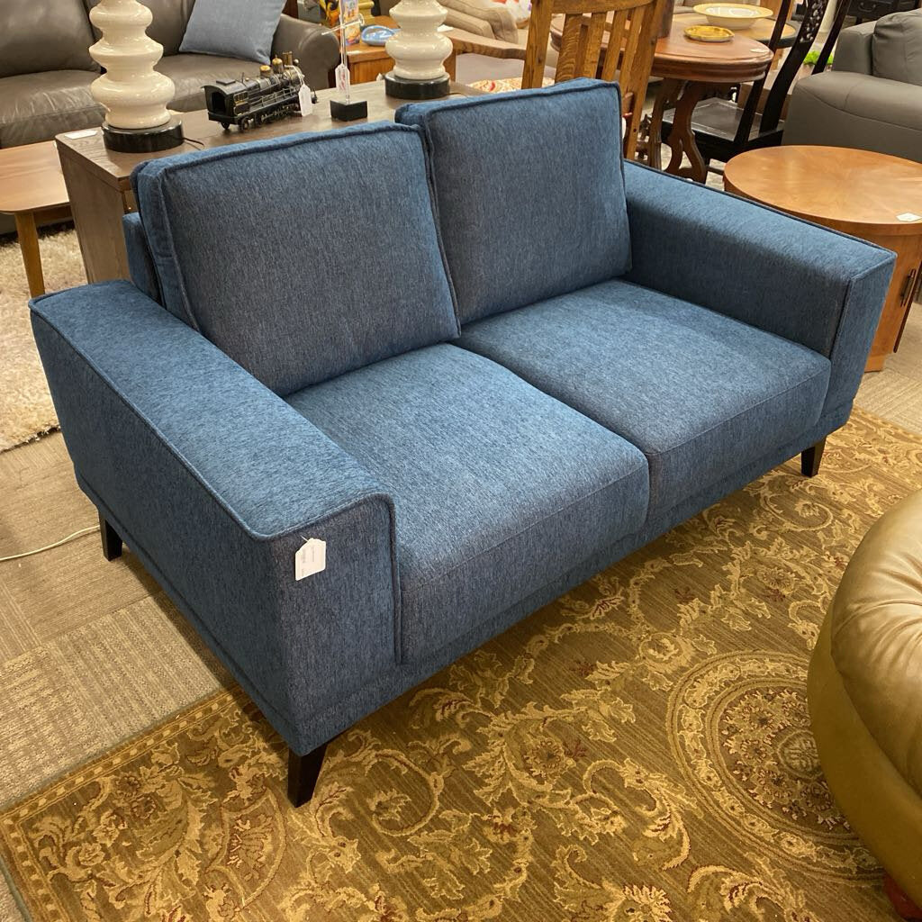Blue sofa in a room with a patterned rug and furniture.